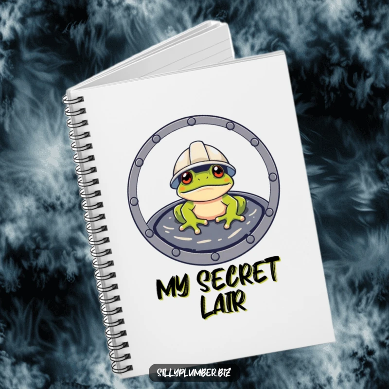 Funny Notebook showing a frog wearing a hard hat, peeking from a manhole, ready for planning.